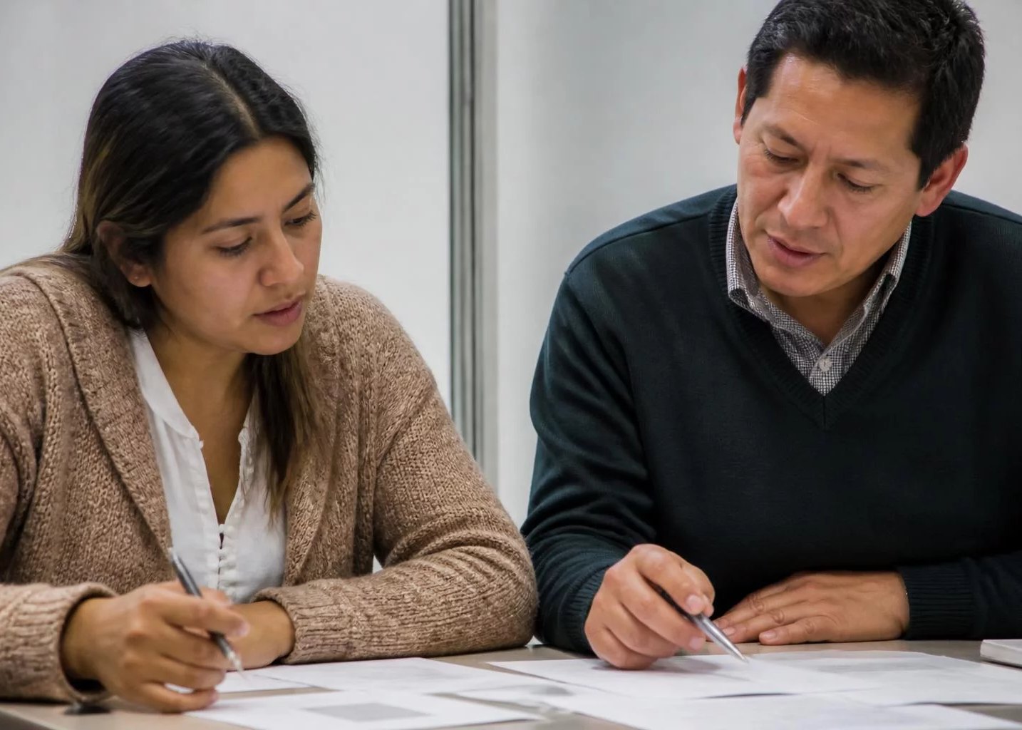 Mesa de seminario con apuntes repartidos y dos personas trabajando